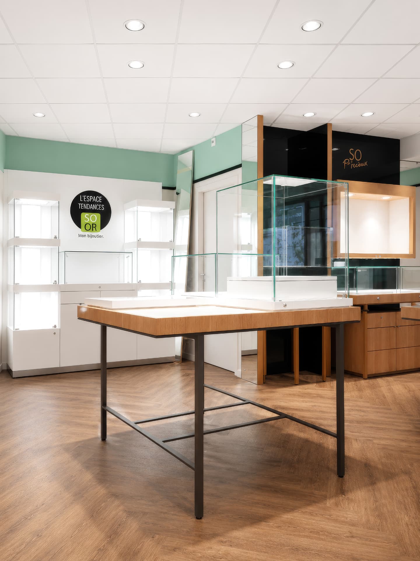 Oak display table with tall glass cube and lit white wall showcases