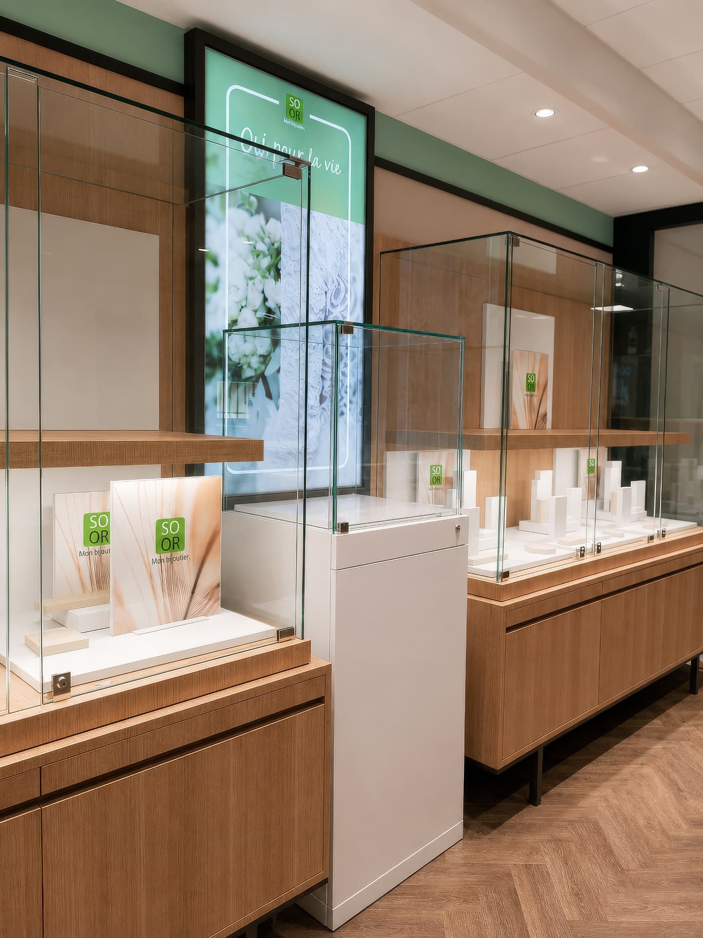 Wall vitrines with oak shelves and a backlit brand graphic panel