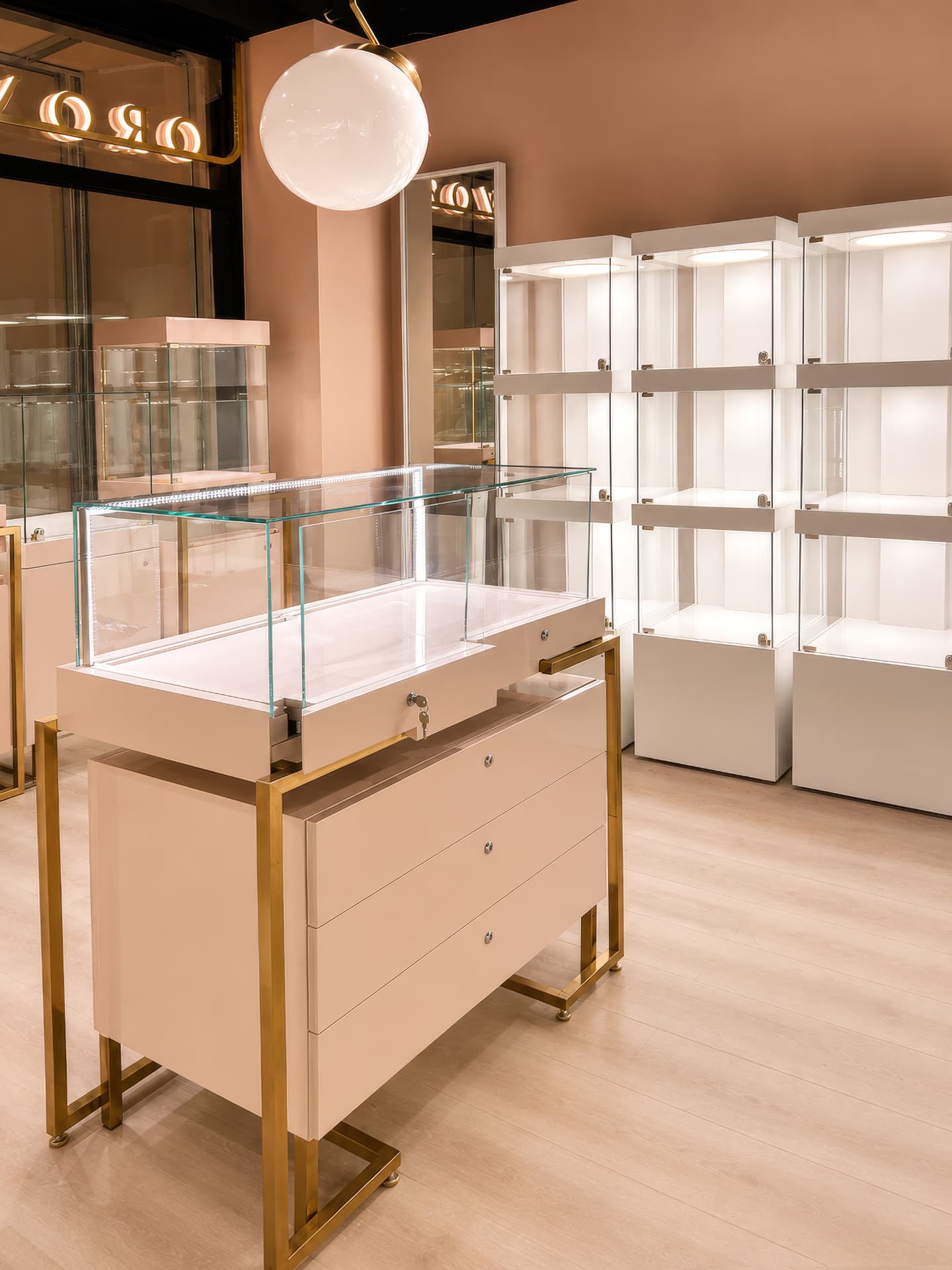 Blush island counter with brass frame and lit white wall vitrines